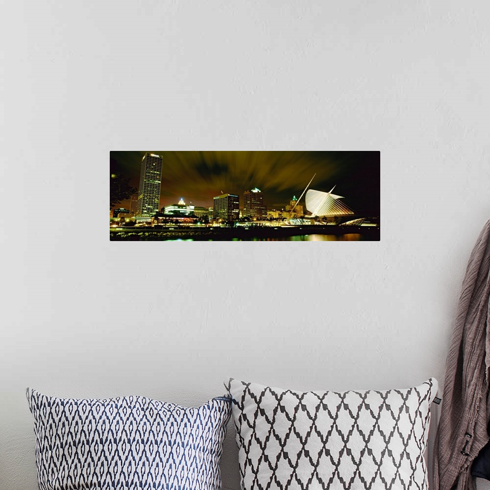 A bohemian room featuring Wide angle photograph from water level of skyline lit up on panoramic wall art.