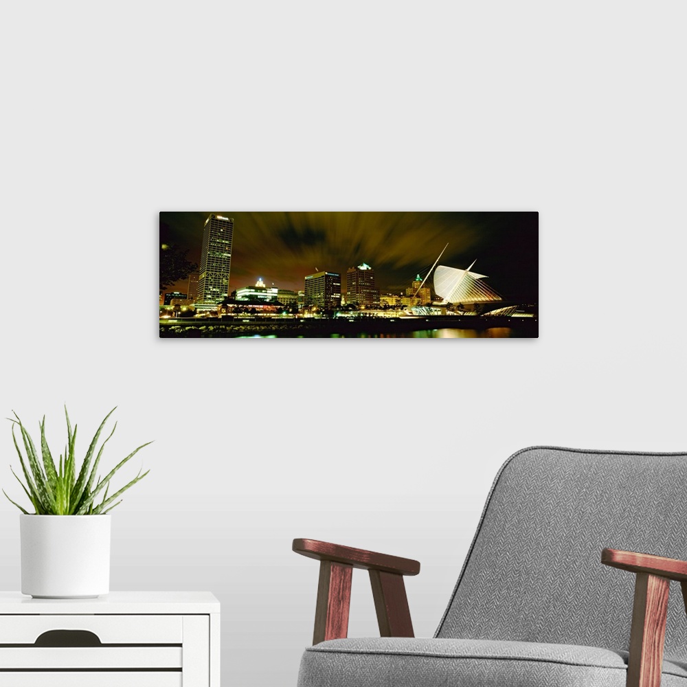 A modern room featuring Wide angle photograph from water level of skyline lit up on panoramic wall art.