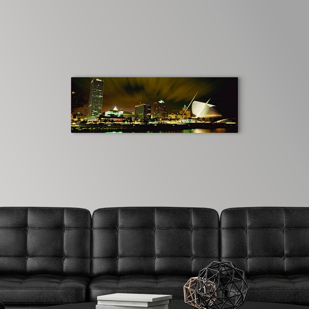 A modern room featuring Wide angle photograph from water level of skyline lit up on panoramic wall art.