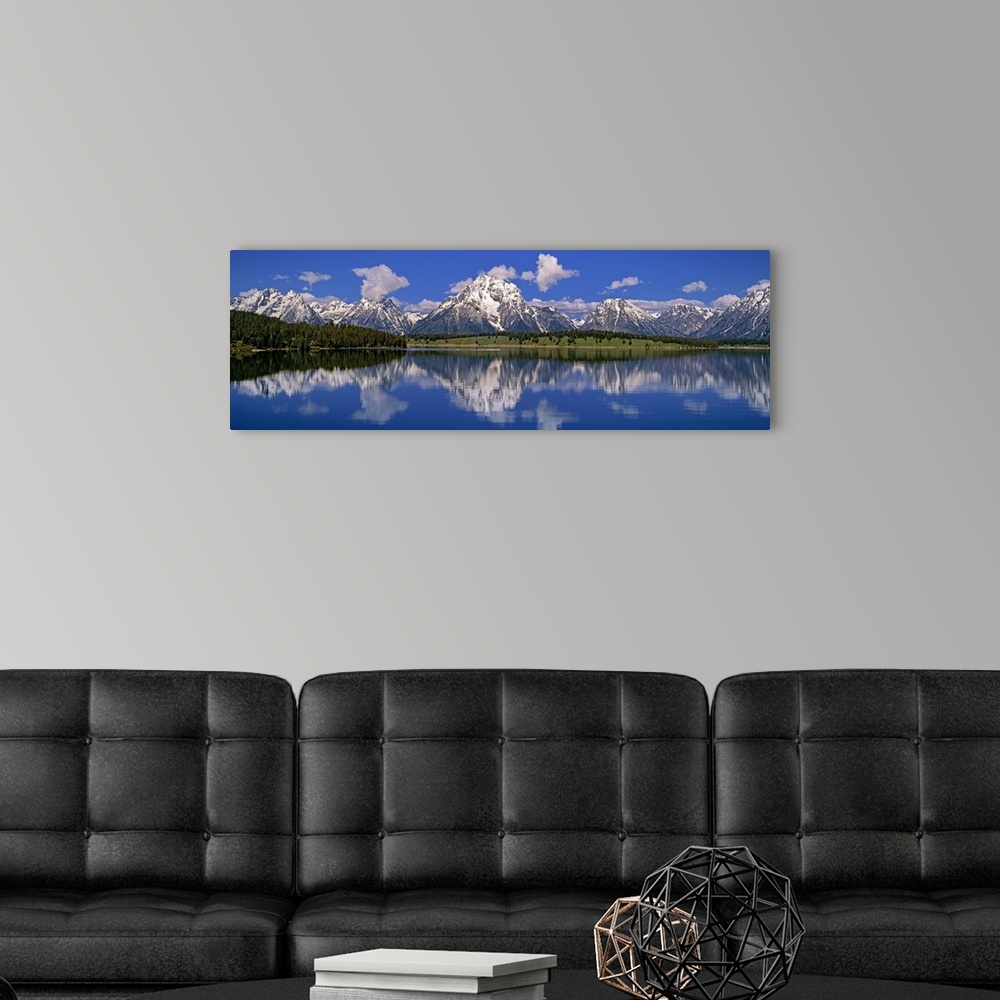 A modern room featuring Large panoramic photo of calm water with rugged snow capped mountains in the distance.