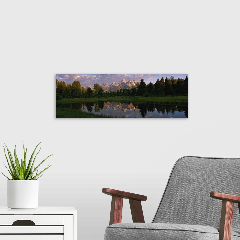 A modern room featuring Panoramic photograph of lake with forest in the background and snow covered mountains in the dist...