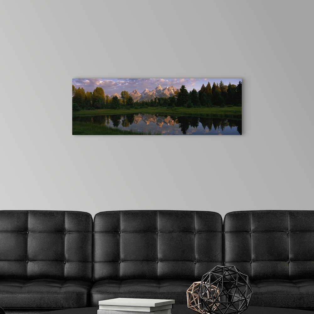 A modern room featuring Panoramic photograph of lake with forest in the background and snow covered mountains in the dist...