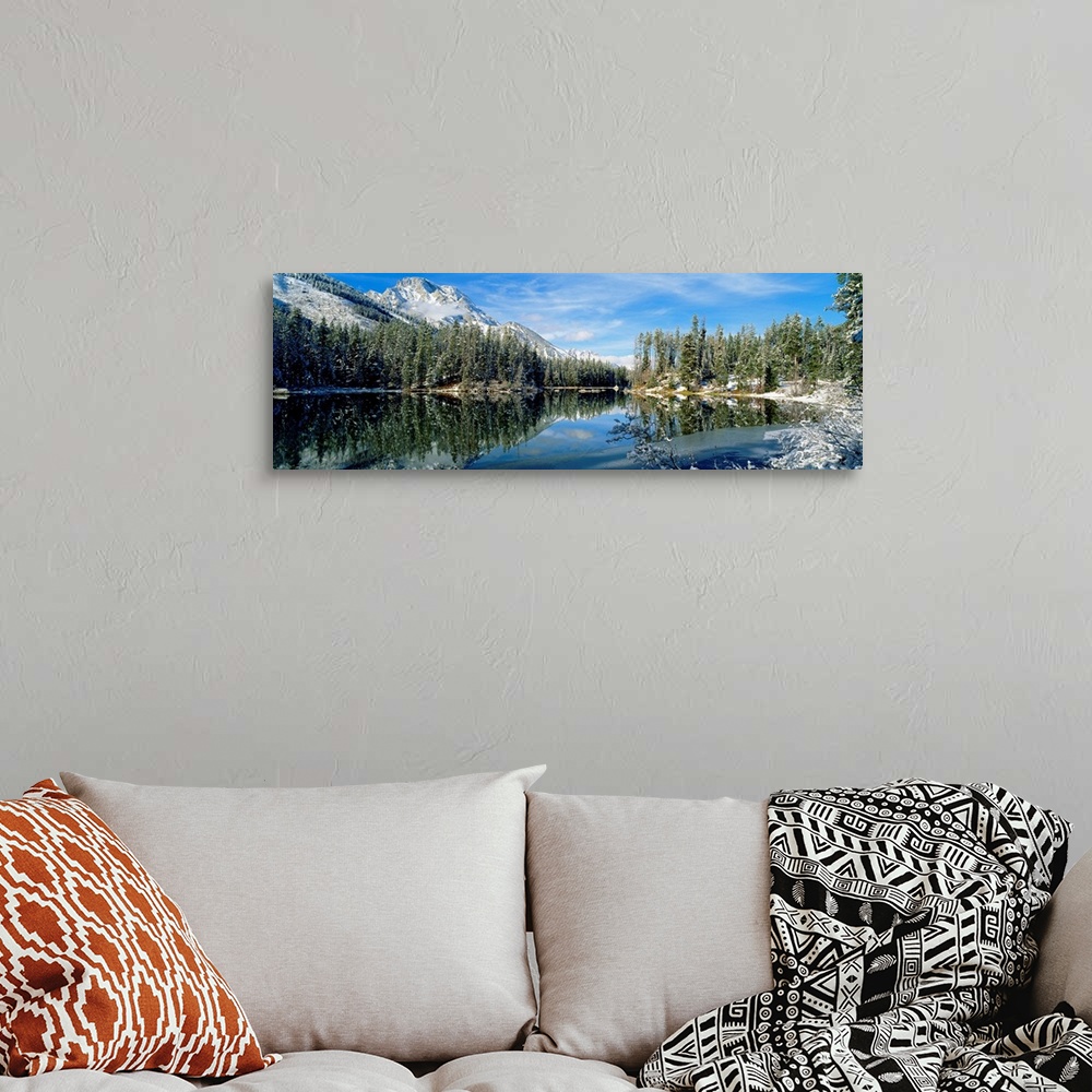 A bohemian room featuring Panorama of a lake in Yellowstone, Wyoming, perfectly mirroring the surrounding evergreen forest ...
