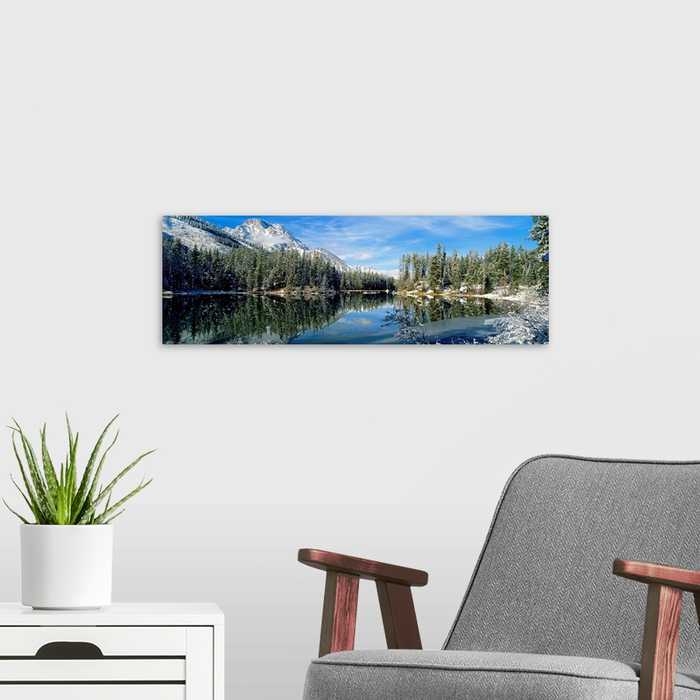 A modern room featuring Panorama of a lake in Yellowstone, Wyoming, perfectly mirroring the surrounding evergreen forest ...