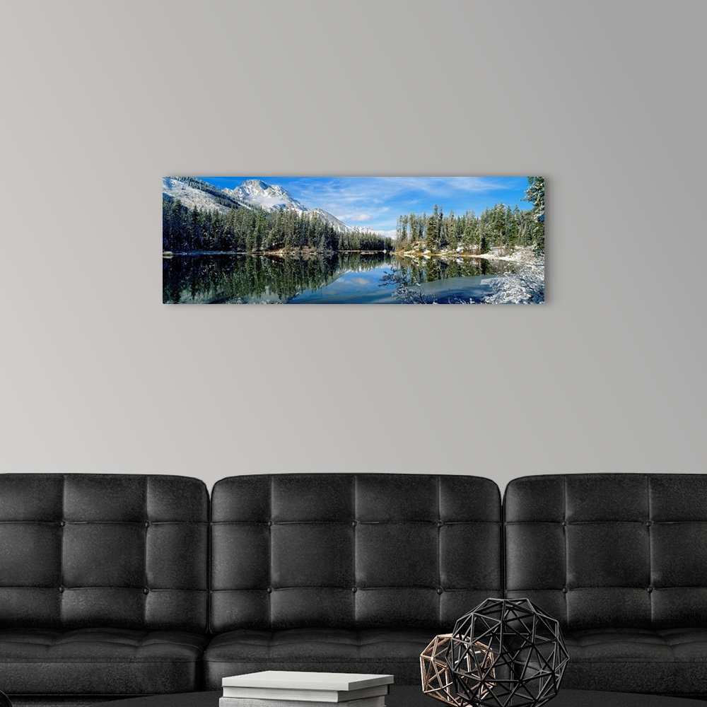 A modern room featuring Panorama of a lake in Yellowstone, Wyoming, perfectly mirroring the surrounding evergreen forest ...