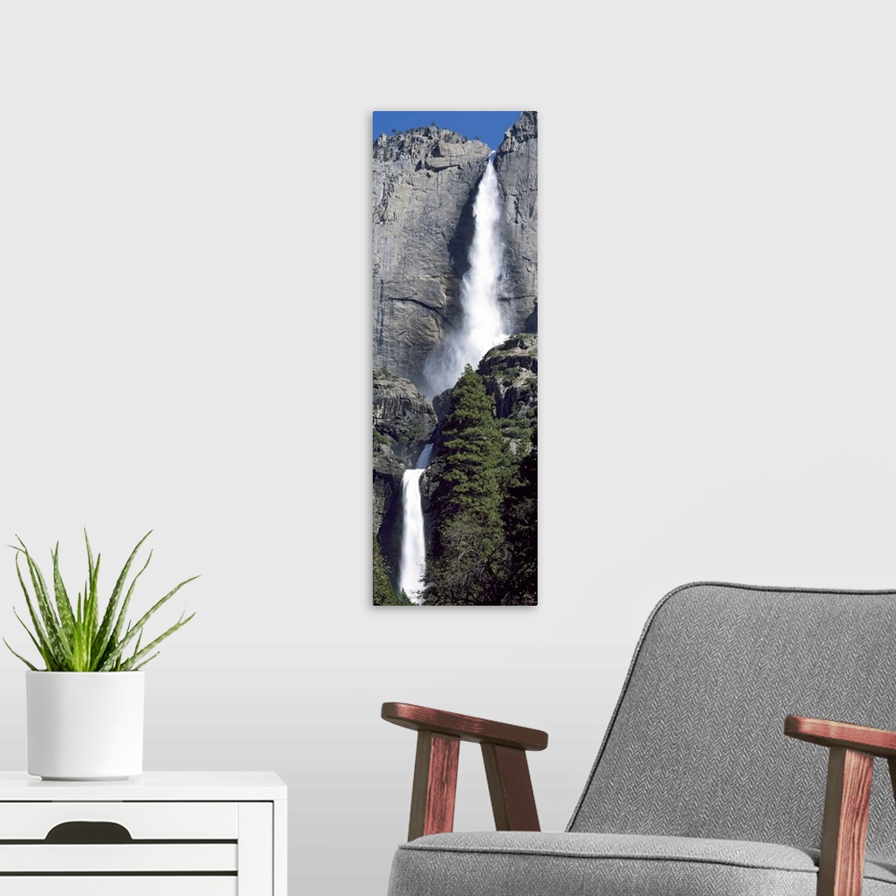 A modern room featuring A narrow and vertical shaped photograph of the majestic Yosemite Falls in late spring with heavy ...