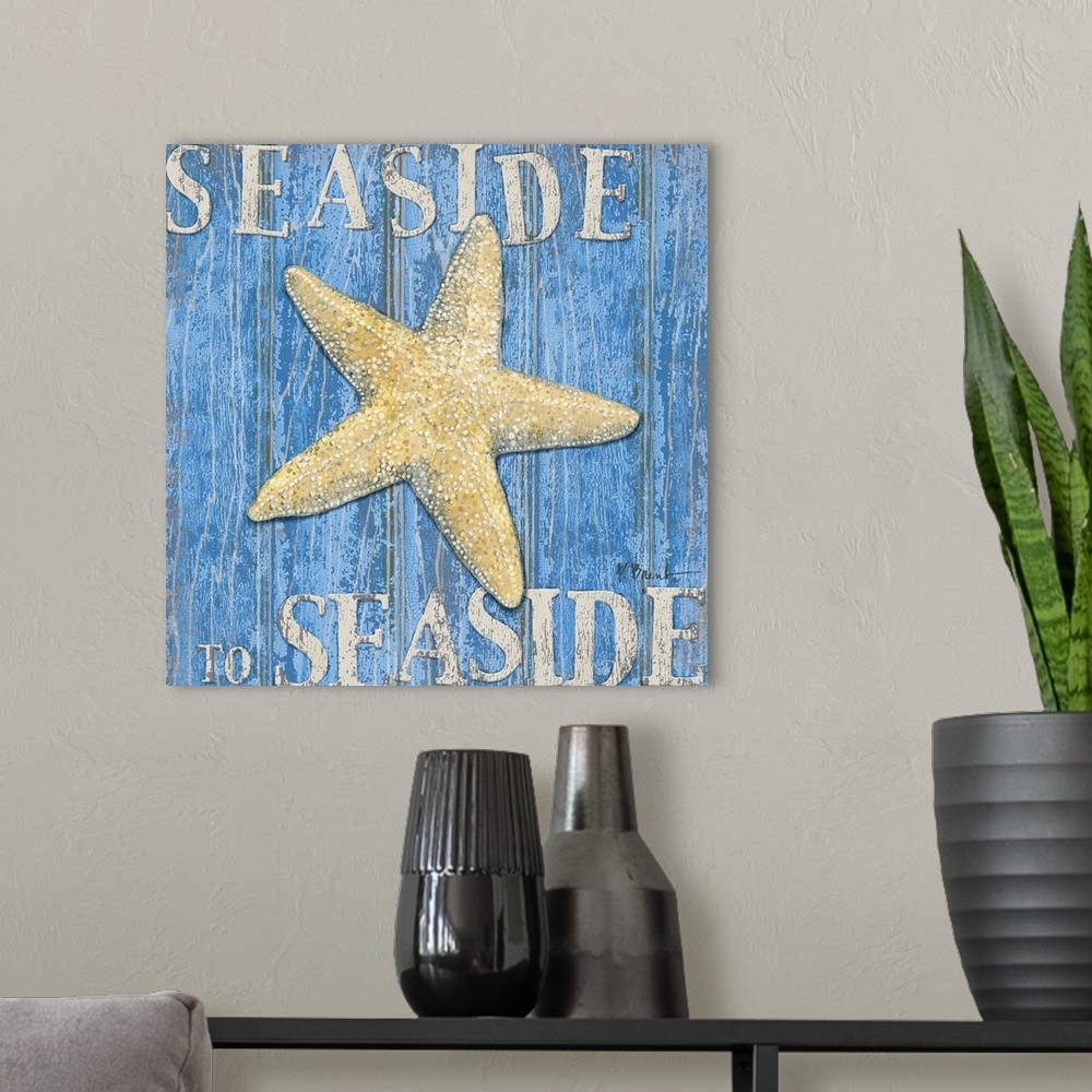 A modern room featuring Square painting of a starfish on blue wood panels with the text Seaside to Seaside.