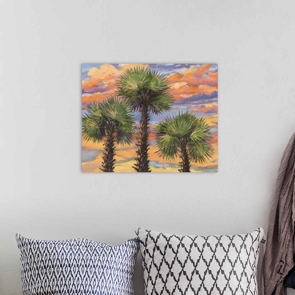 A bohemian room featuring A group of three palm trees against clouds illuminated by the sunset.