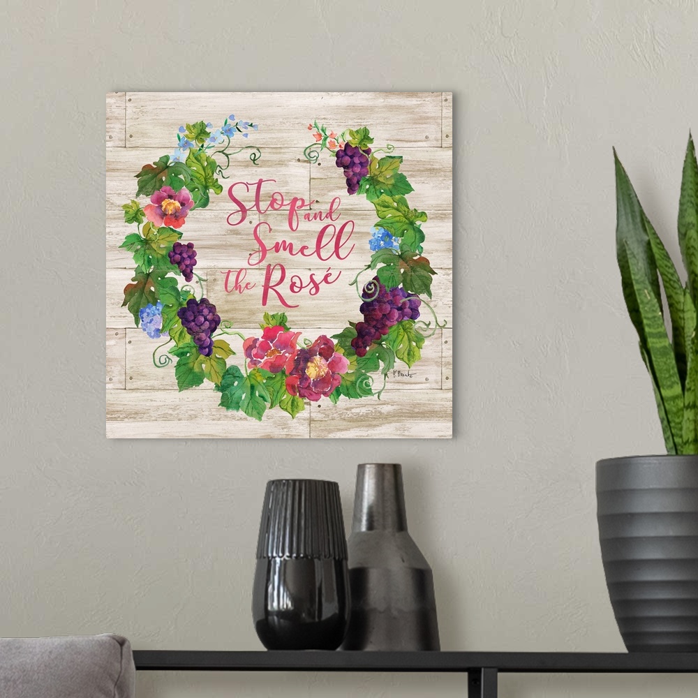 A modern room featuring "Stop and Smell the Rose" written in the center of a floral wreath with grapes on a faux wood bac...