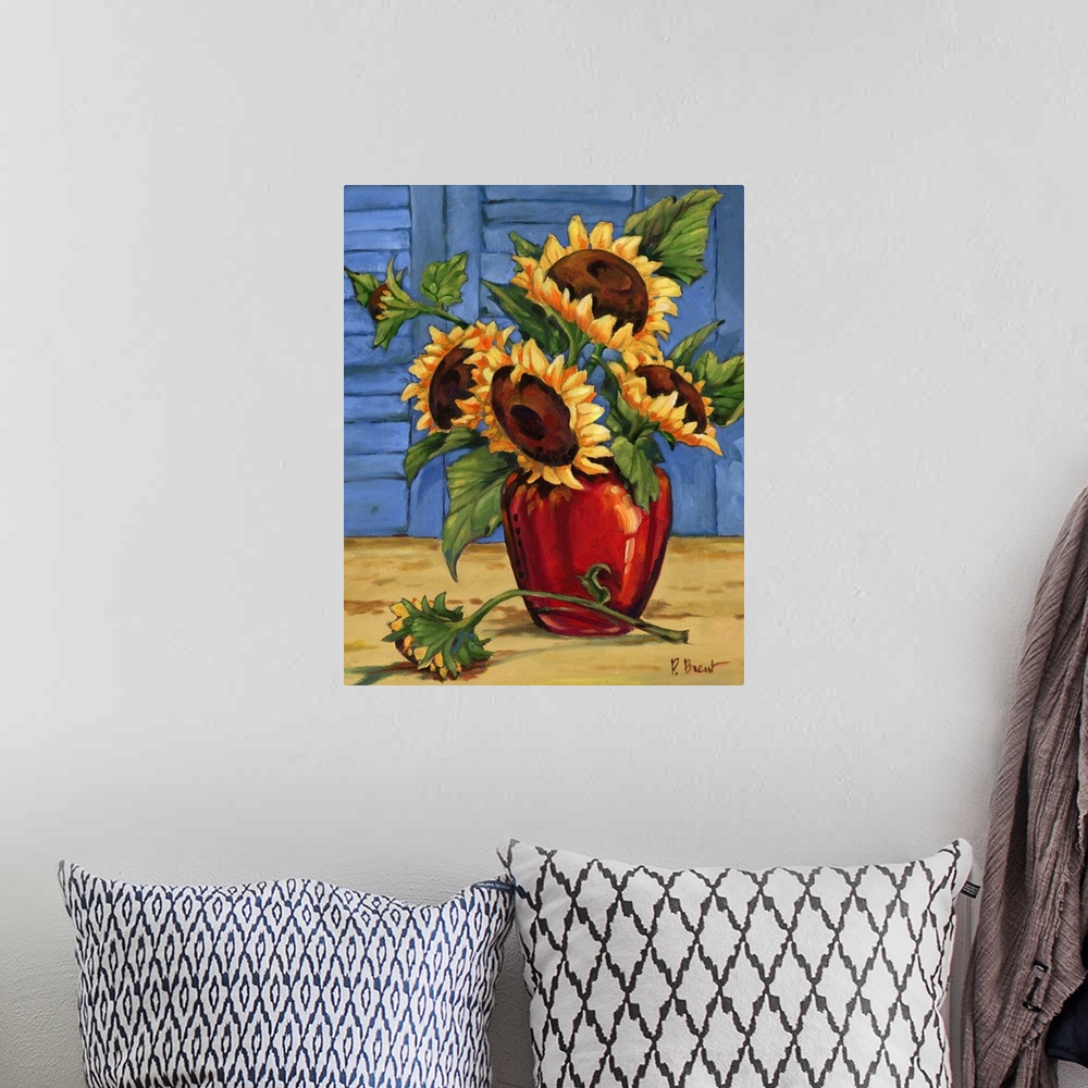 A bohemian room featuring Still life painting of an arrangement of sunflowers in a red vase against window shutters.