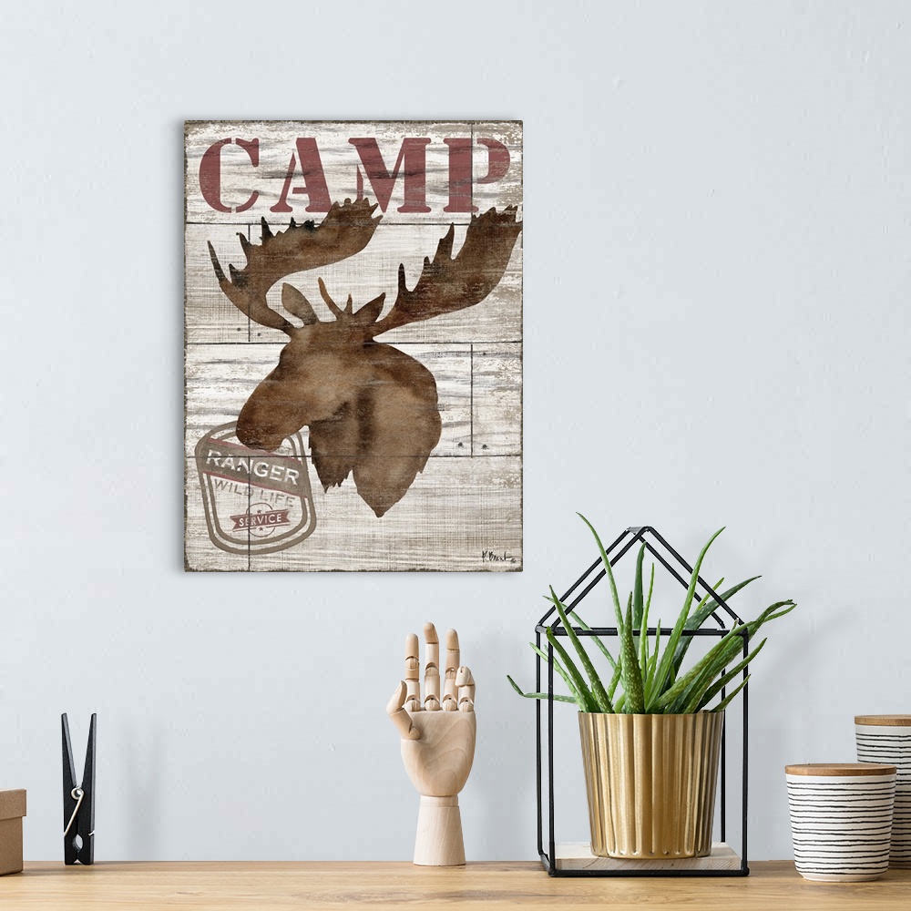 A bohemian room featuring Contemporary decorative artwork of a moose silhouette with the word "camp" on a textured wooden b...