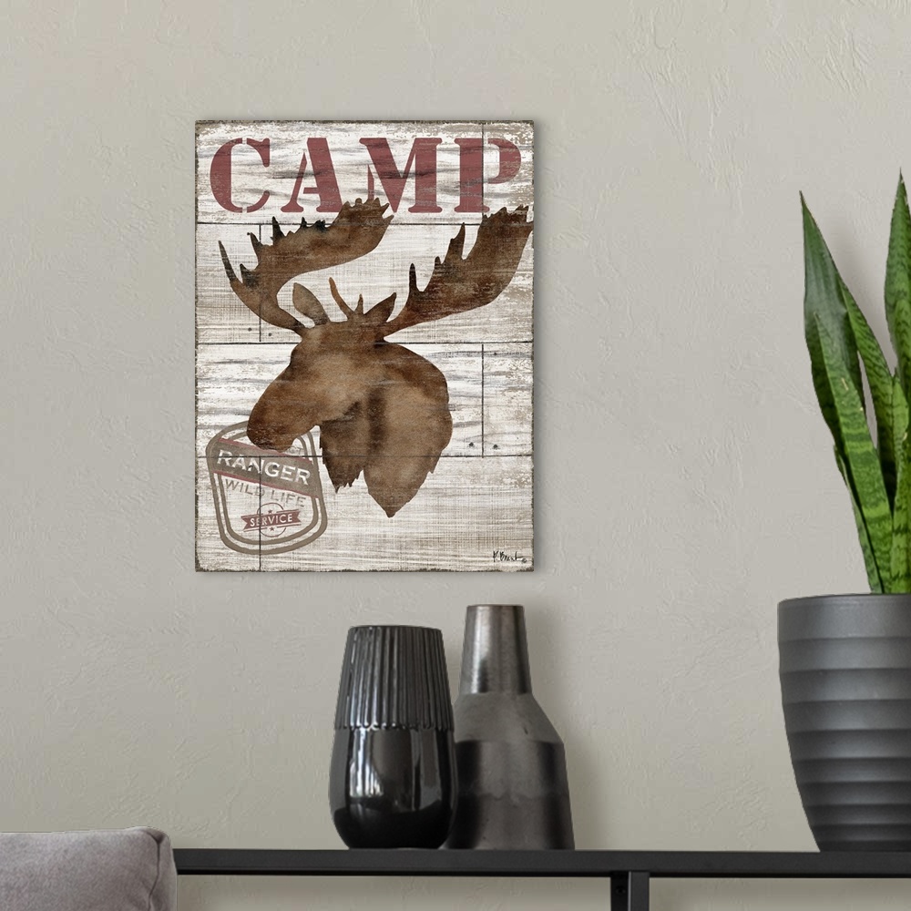 A modern room featuring Contemporary decorative artwork of a moose silhouette with the word "camp" on a textured wooden b...