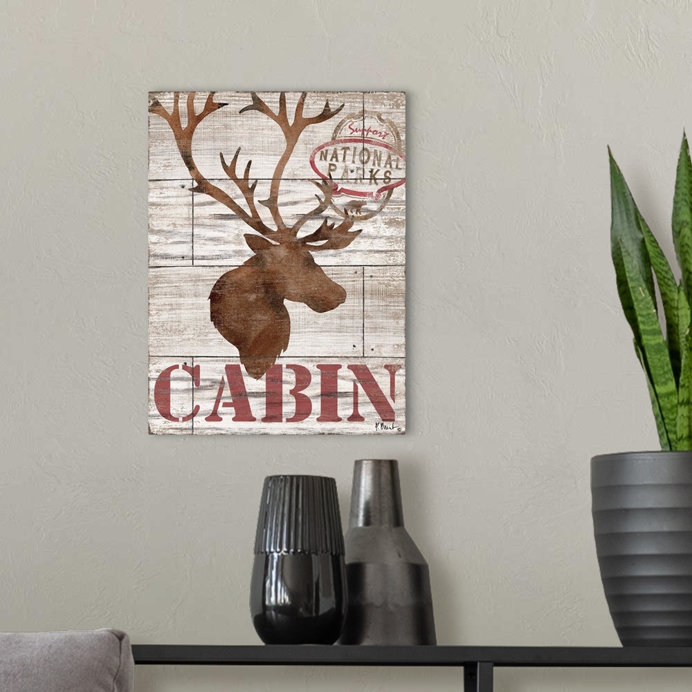 A modern room featuring Contemporary decorative artwork of an elk silhouette with the word "cabin" on a textured wooden b...