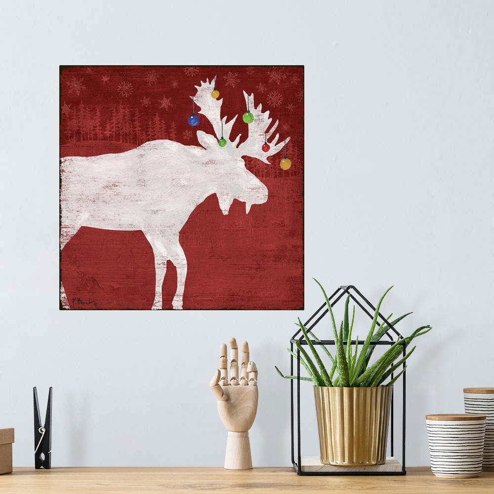 A bohemian room featuring White silhouette of a moose with ornaments on its antlers on a red forest backdrop.
