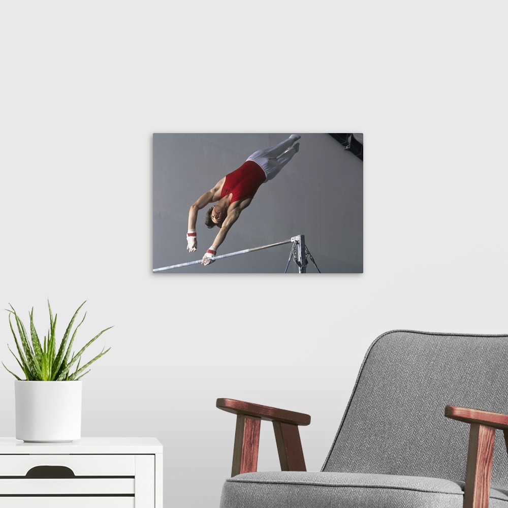 A modern room featuring Male gymnast on the horizontal bar