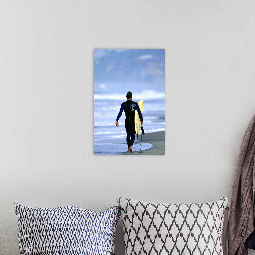 A bohemian room featuring Male surfer walking on the beach in San Diego, CA