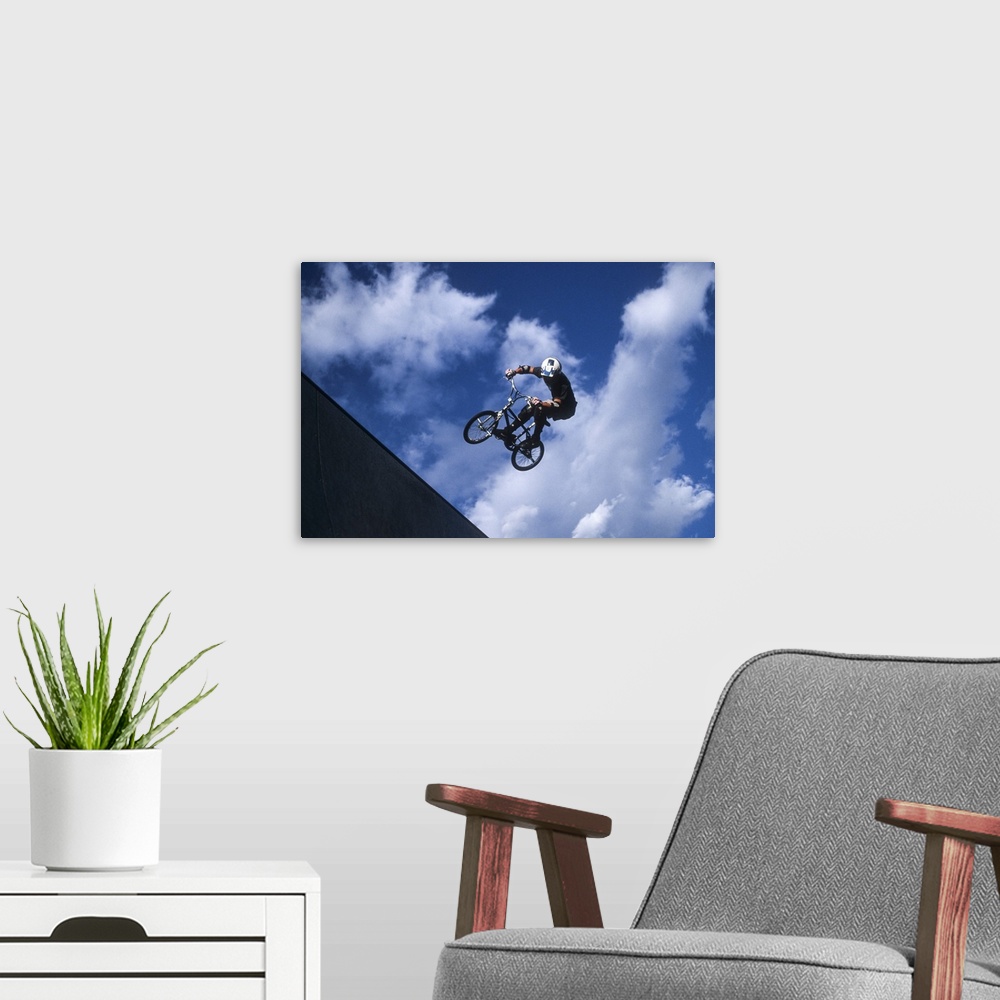 A modern room featuring Teenage boy flies over the vert on a BMX bike