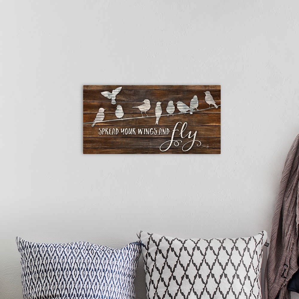 A bohemian room featuring "Spread Your Wings and Fly" with a design of birds on a line on a brown wood plank background.