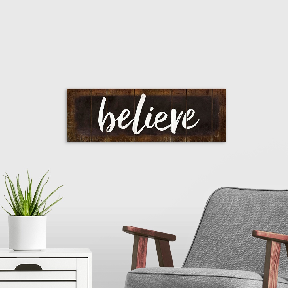 A modern room featuring "Believe" in white handlettered script on a weathered brown background.