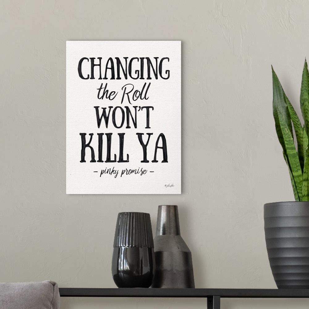 A modern room featuring Humorous decorative artwork featuring the phrase: Changing the roll won't kill ya, pinky promise.