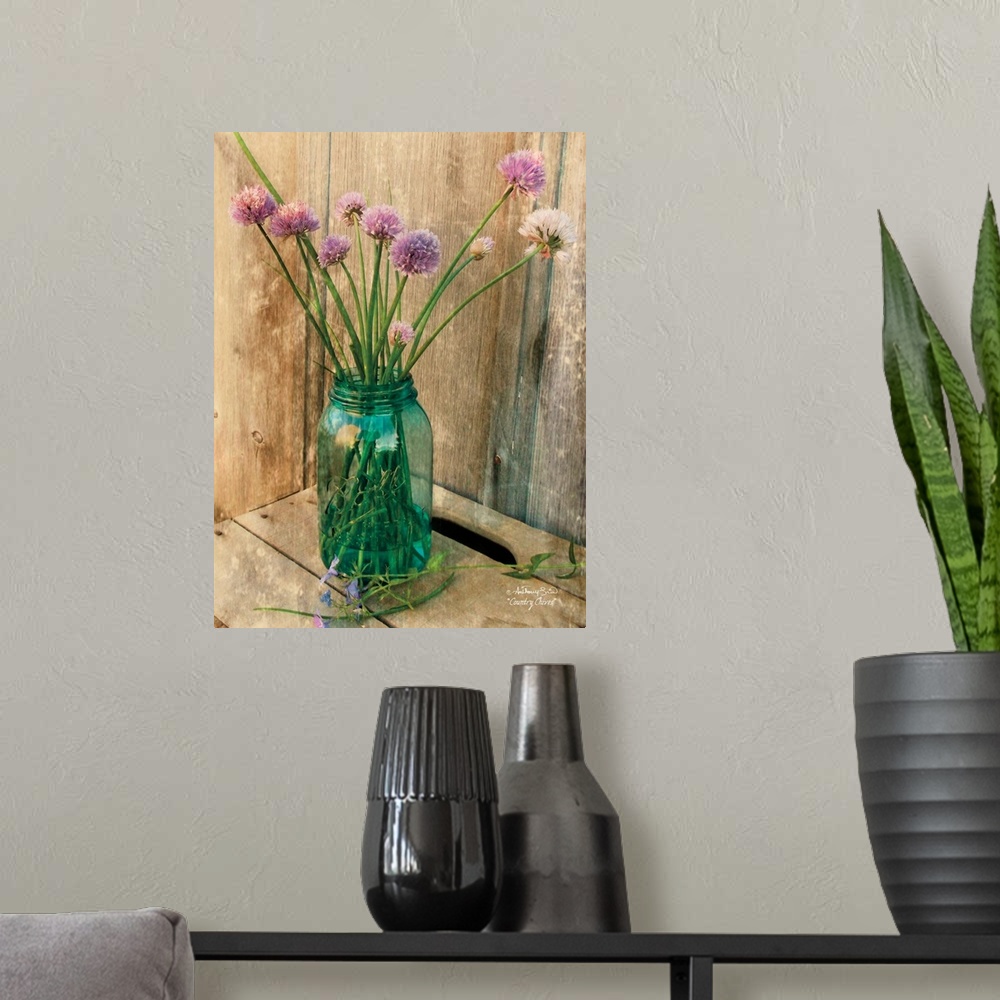 A modern room featuring Decorative artwork with a bouquet of purple flowers in a ball mason jar vase over a distressed wo...
