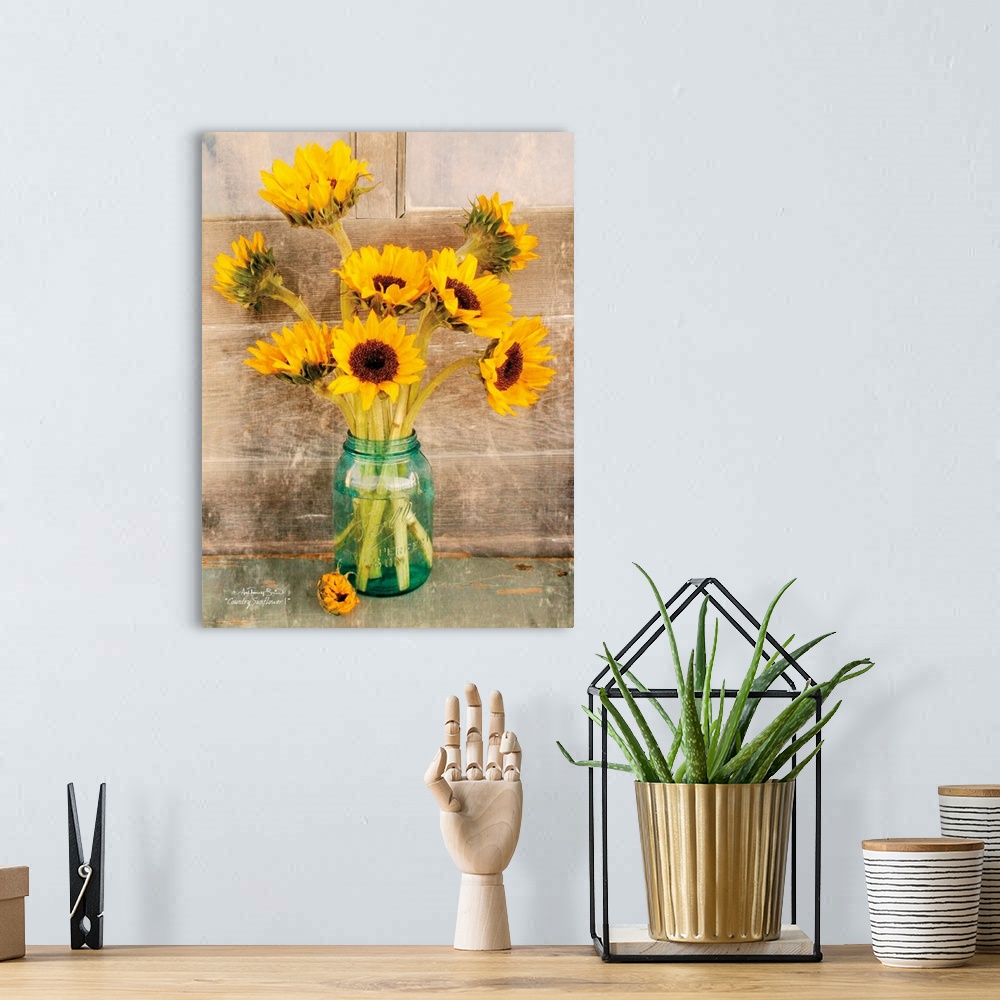 A bohemian room featuring Decorative artwork with a bouquet of sunflowers in a ball mason jar vase over a distressed wood b...