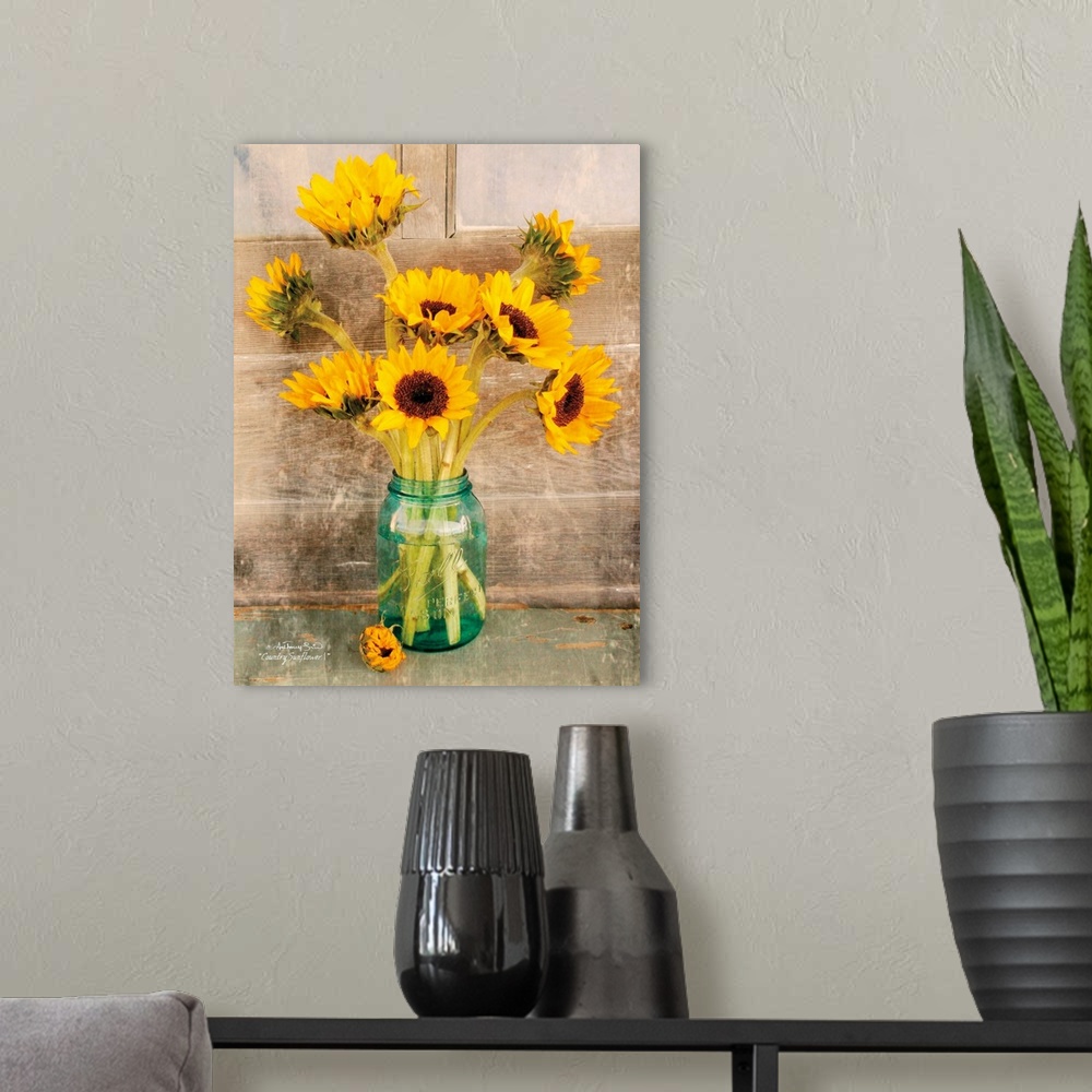 A modern room featuring Decorative artwork with a bouquet of sunflowers in a ball mason jar vase over a distressed wood b...