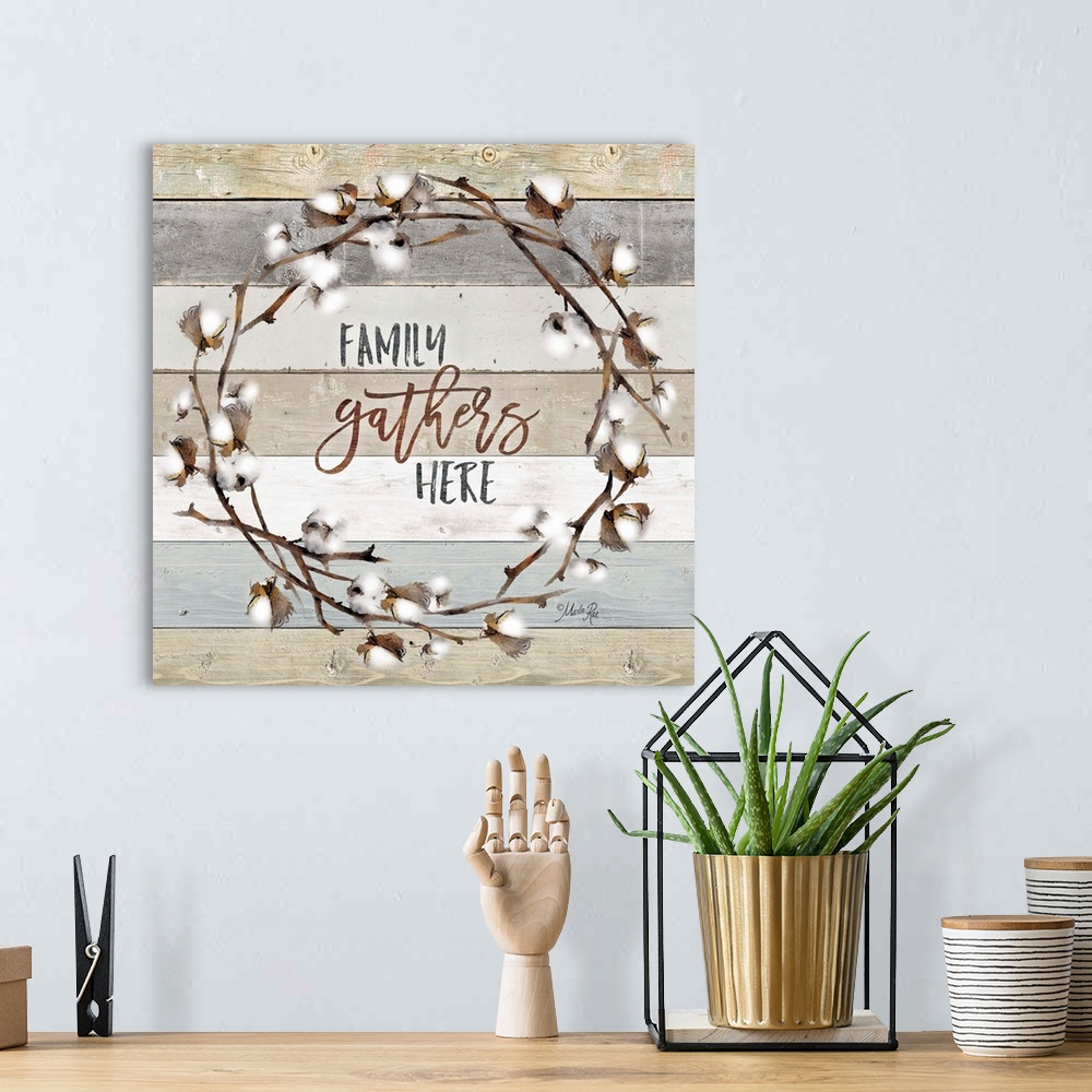 A bohemian room featuring "Family Gathers Here" in the middle of a wreath of cotton against a shiplap background.