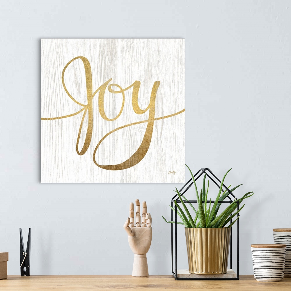 A bohemian room featuring The word Joy is gold colored letters over white background with wood grain texture overlaid.