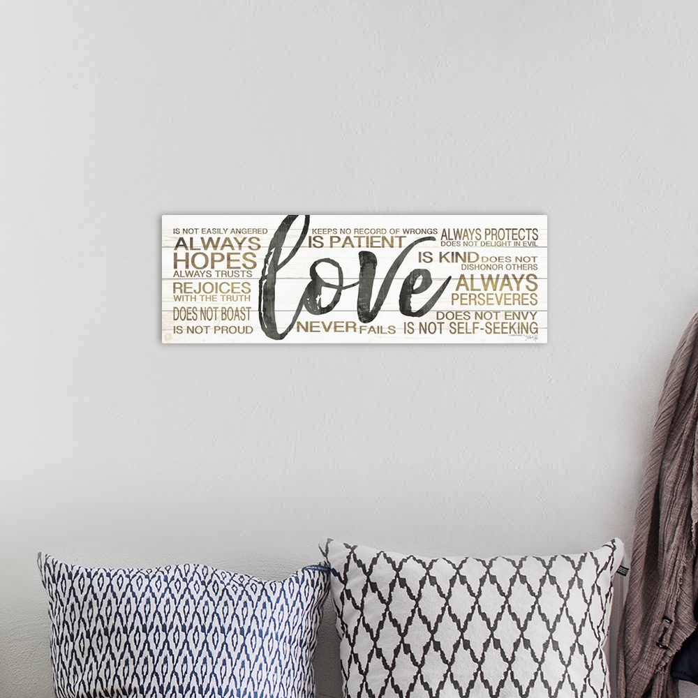 A bohemian room featuring Typography artwork of the word "love" in large black script, surrounded by 1 Corinthians 13:4.