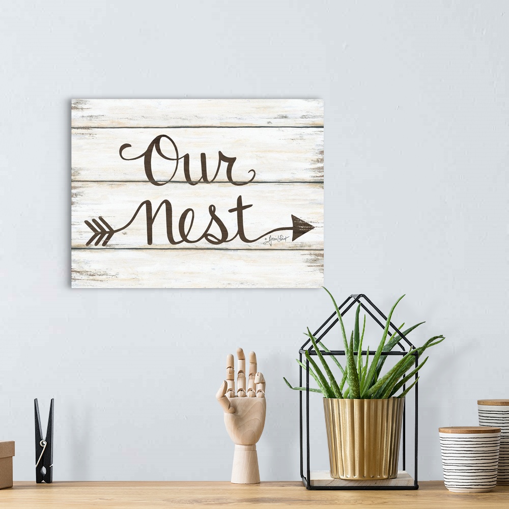 A bohemian room featuring This decorative artwork features the phrase: our nest, over a distressed wood planks.