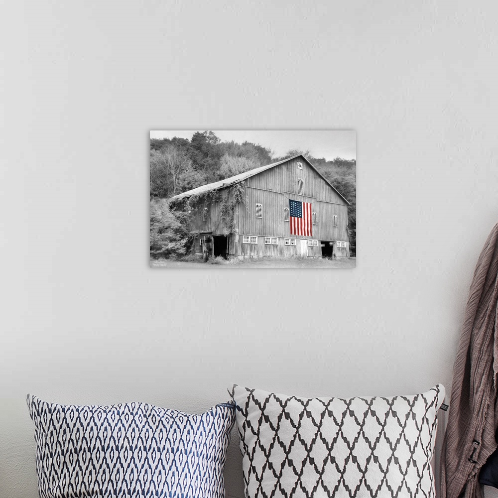 A bohemian room featuring Black and white photo of a barn with an American Flag in color hanging on the side.