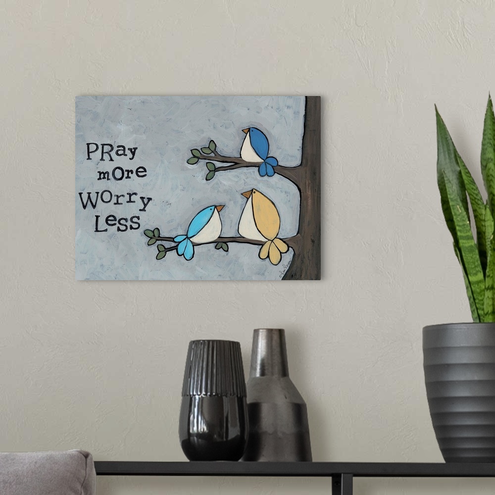 A modern room featuring Artwork of three birds in a tree with the words "pray more, worry less."