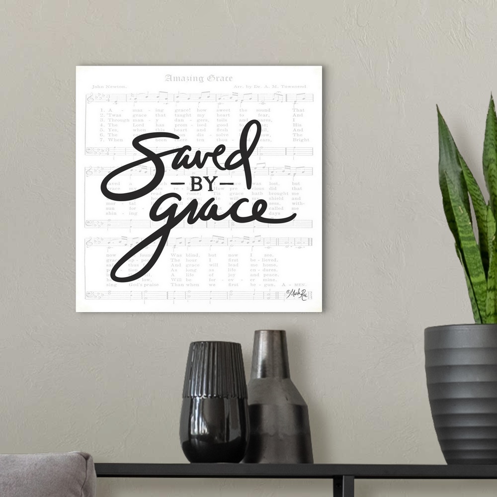 A modern room featuring Typography of the phrased "saved by grace" with the sheet music for Amazing Grace in the background.