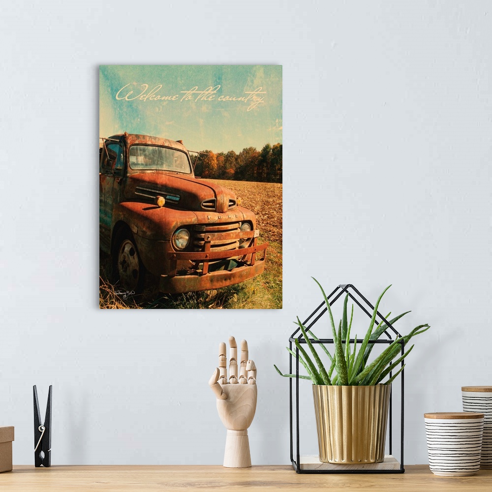 A bohemian room featuring The words: Welcome to the country, are placed over rusted pick-up truck with distressing throughout.