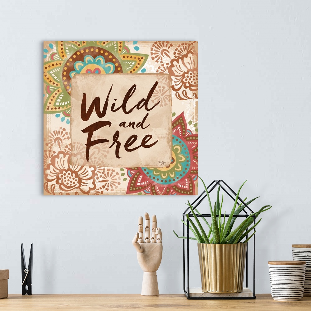A bohemian room featuring "Wild and Free" hand written and framed by colorful floral mandalas.