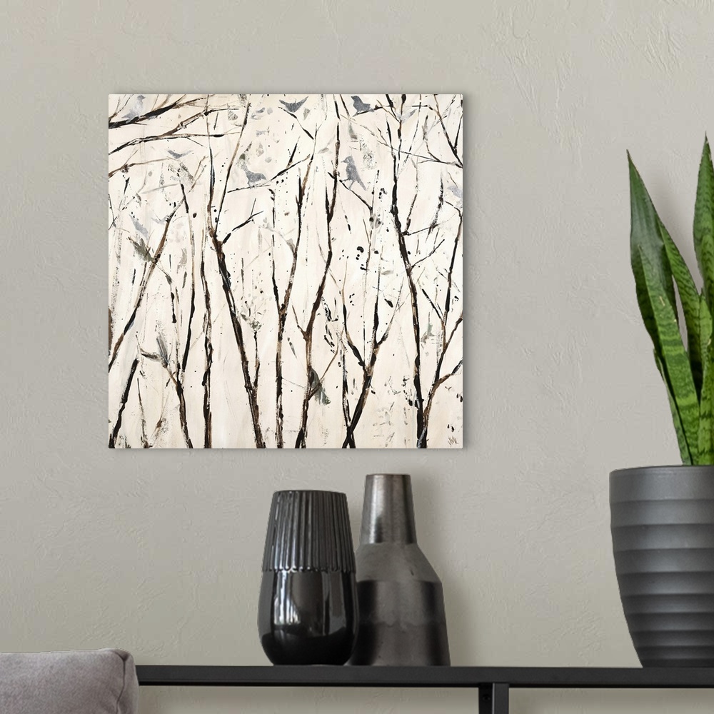 A modern room featuring Square painting in neutral white and brown hues with silver birds perched on bare branches.