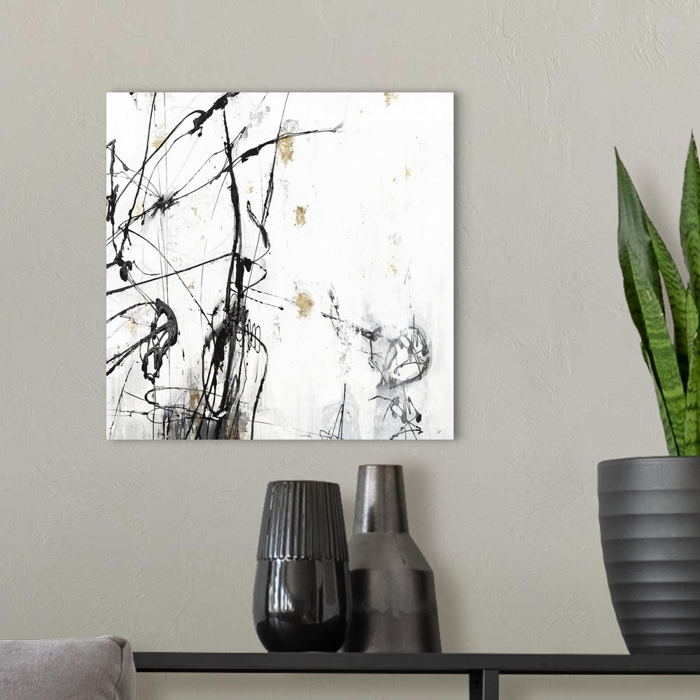 A modern room featuring Square abstract painting in white, gray, black, and gold with thin lines sporadically on top of t...