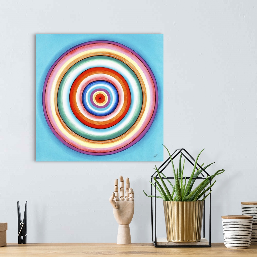 A bohemian room featuring A contemporary painting of concentric circles in a variety of colors against a light blue backgro...