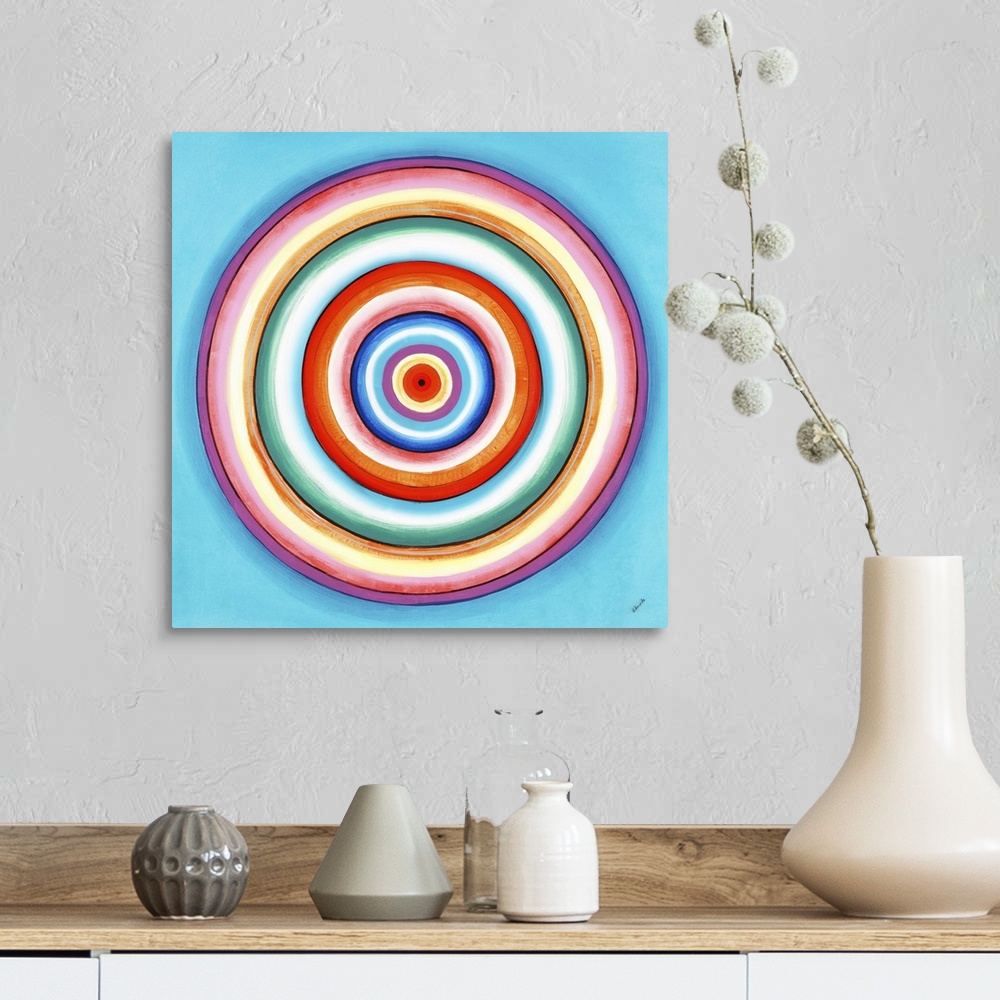 A farmhouse room featuring A contemporary painting of concentric circles in a variety of colors against a light blue backgro...