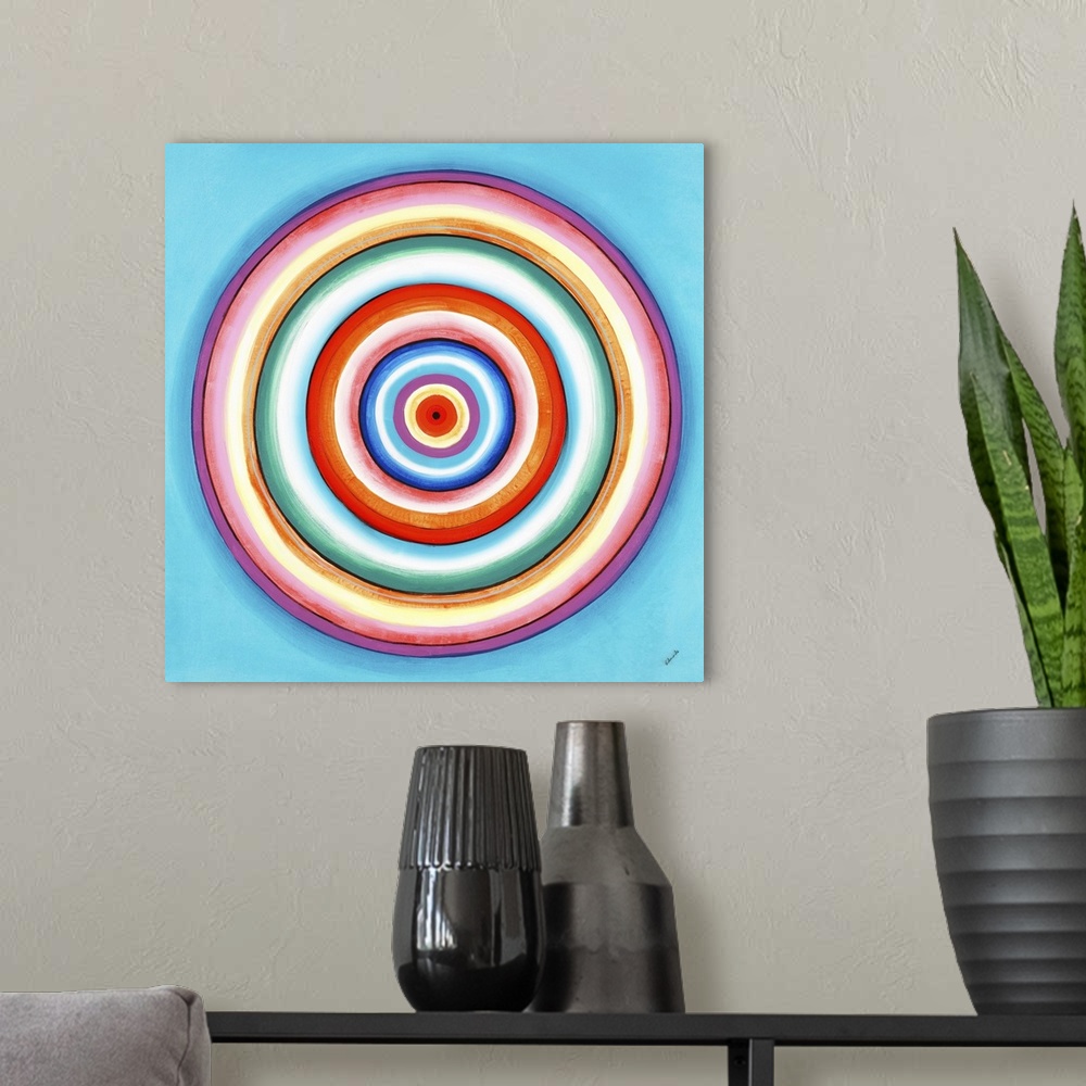 A modern room featuring A contemporary painting of concentric circles in a variety of colors against a light blue backgro...