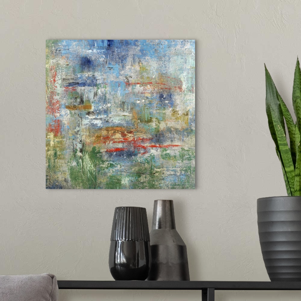 A modern room featuring Square abstract painting in blue, green, red, gold, and gray hues.