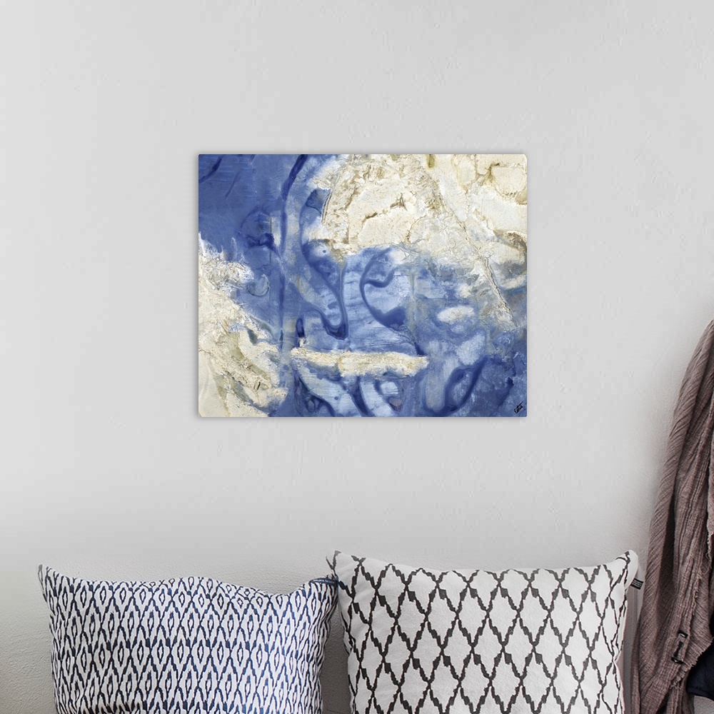 A bohemian room featuring Blue, gold, and silver painting resembling an aerial view of the ocean and sandbars.