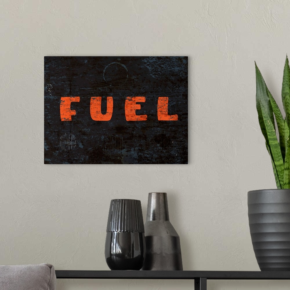 A modern room featuring Graphic rusty wall art of distressed typography with the the word FUEL large, in orange, and in c...