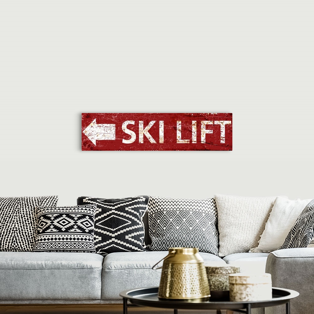 A bohemian room featuring A worn, distressed, cracked and rusty ski lift arrow sign in red.