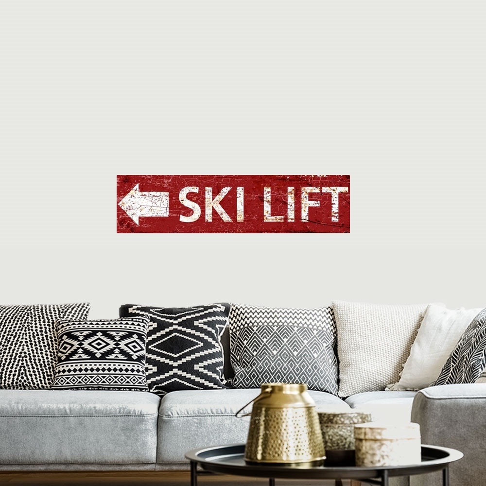A bohemian room featuring A worn, distressed, cracked and rusty ski lift arrow sign in red.