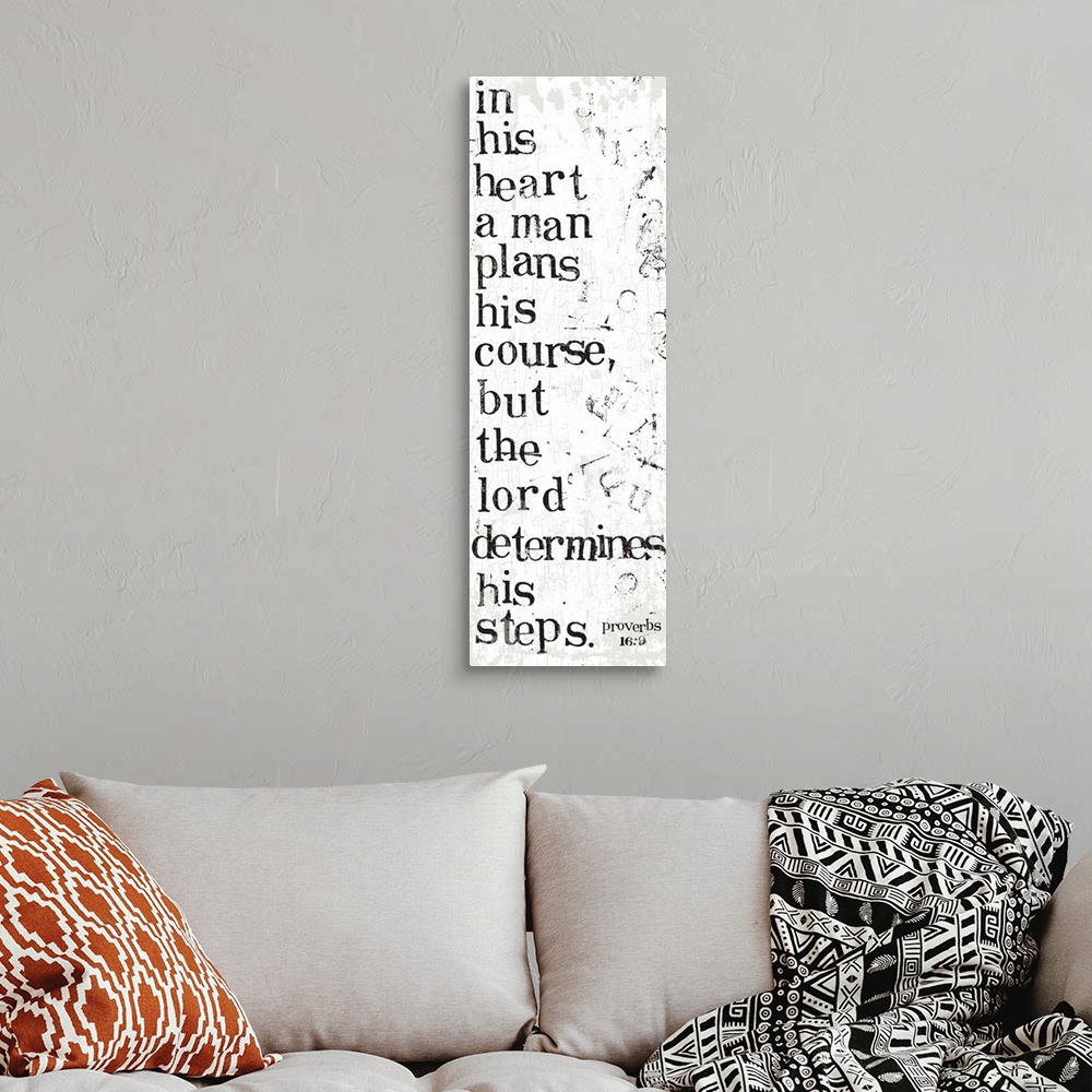 A bohemian room featuring Distressed black and white letter-stamped Bible verse scripture of Proverbs 16:9 In his heart a m...