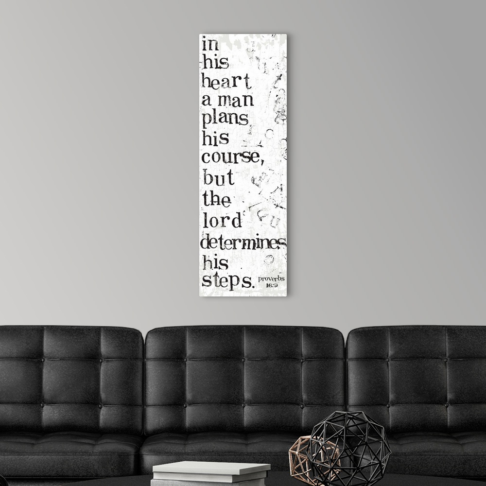 A modern room featuring Distressed black and white letter-stamped Bible verse scripture of Proverbs 16:9 In his heart a m...