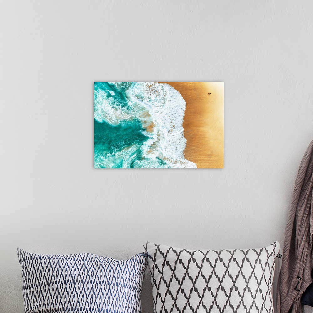A bohemian room featuring A stunning overhead aerial photograph of bright turquoise waves crashing onto a sandy beach