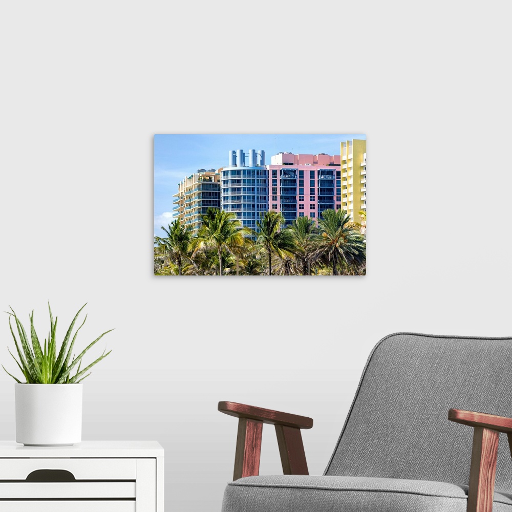 A modern room featuring Multi colored buildings behinda row of palm trees in Miami, Florida.
